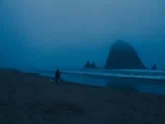 Photo of a walker along Cannon Beach in Oregon.