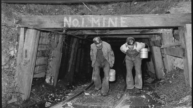 An archival photo of miners emerging from a mine shaft.
